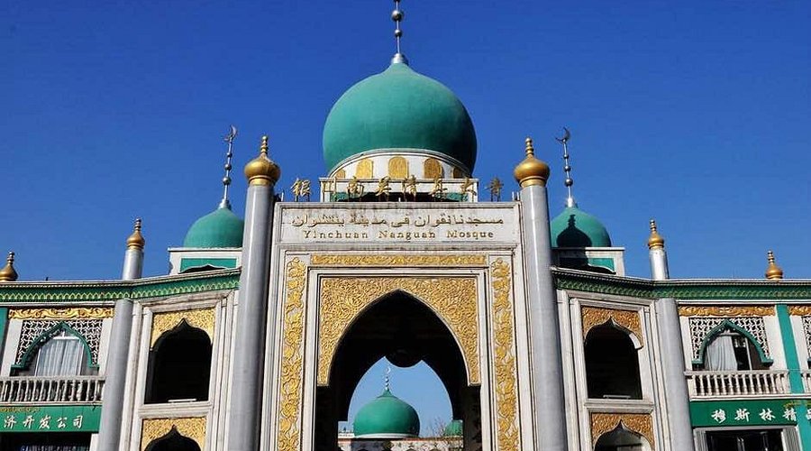 A majestic mosque with prominent domes and intricate golden detailing on the arc