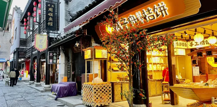 汴河街商业街景，两侧仿古店铺沿街排开，游客穿行其间