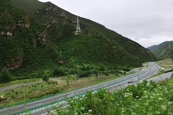 共玉高速在冻土区蜿蜒穿行，路面上方是青藏高原的起伏山峦